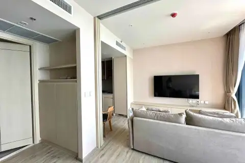 1 Bedroom Condo for Rent at Arom Wongamat living room with gray sofa, wall-mounted TV, and storage closet