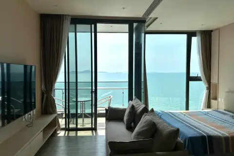 1 Bedroom Condo for Rent at Arom Wongamat living area with sofa, TV, and balcony overlooking the sea