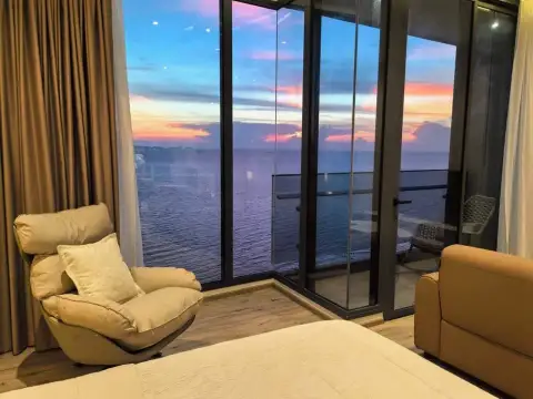 1 Bedroom Condo for Sale at Arom Wongamat bedroom seating area with panoramic ocean sunset view