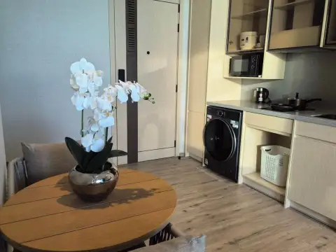 1 Bedroom Condo for Sale at Arom Wongamat dining table with orchid beside kitchenette and washer