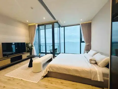 1 Bedroom Condo for Rent at Arom Wongamat king bed facing floor-to-ceiling windows with ocean view