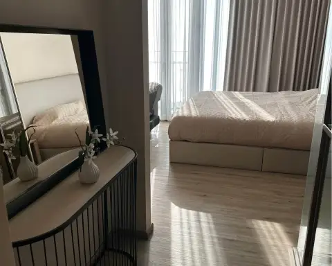 1 Bedroom Condo for Rent at Arom Wongamat bedroom with console mirror, orchid vase and natural light