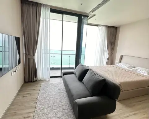 1 Bedroom Condo for Rent at Arom Wongamat bedroom with sofa, wall-mounted TV and balcony sea view
