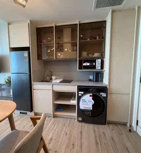 1 Bedroom Condo for Rent at Arom Wongamat compact kitchen with fridge, washer, and built-in cabinets