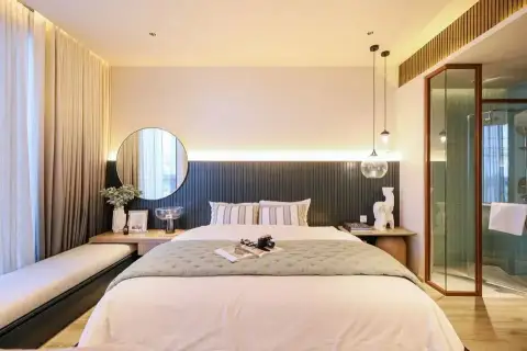 1 Bedroom Condo for Sale at Arom Wongamat bedroom with round mirror, pendant lights and glass-enclosed shower