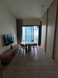 1 Bedroom Condo for Sale at Arom Wongamat living area with dining table and floor-to-ceiling sea view window