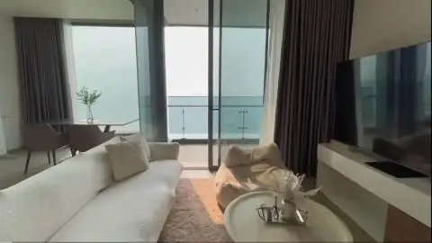 2 Bedroom Condo for Rent at Arom Wongamat lounge with white sofas, TV console and balcony access