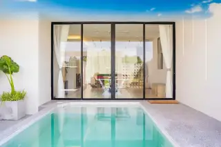Aura Villa Reserve private plunge pool with glass sliding doors leading to an indoor living area.