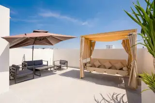 Aura Villa Reserve rooftop terrace with a large umbrella, outdoor seating, and a daybed canopy.