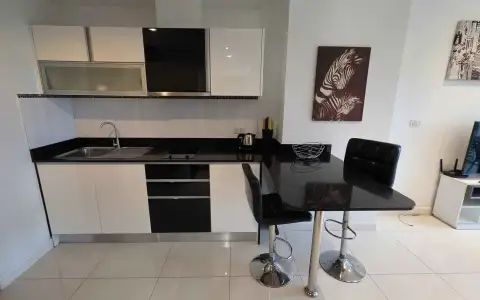 1 Bedroom Condo for Rent at Axis Pattaya Condo kitchen with black countertop and bar table seating