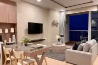 1 Bedroom Condo for Sale at Cetus Beachfront dining and living area with glass-top table, gray sofa, wall TV, and night sea view balcony