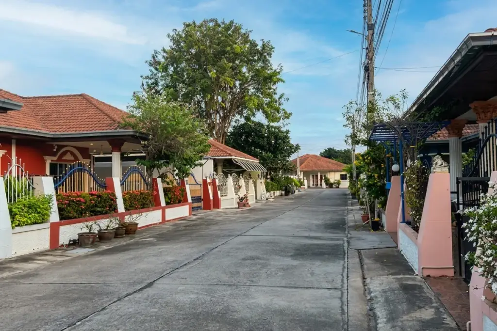 Eakmongkol Chaiyapruek1 exterior with yellow walls, green lawn, palm trees, and a covered entrance with white columns.