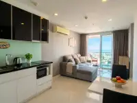 1 Bedroom Condo for Sale at The Vision living area with kitchenette, sofa, and ocean view through balcony windows