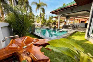 SP Village 3 tropical garden with private pool, sun loungers, wooden sculpture and shaded sala pavilion