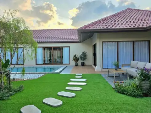 4 Bedroom House for Rent at Baan Balina 3 backyard with stepping stone path, lawn, and pool at dusk
