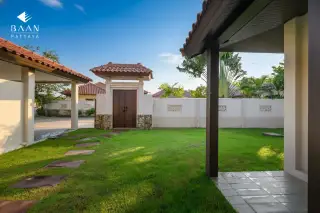 Baan Balina 3: Lush green lawn with stepping stones leading to a traditional wooden gate and white wall.