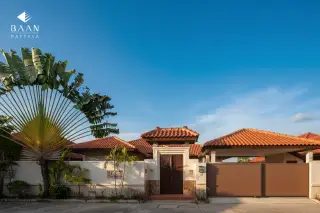 Baan Balina 3: Front view of the property entrance with a traditional wooden gate, fence, and palm trees.