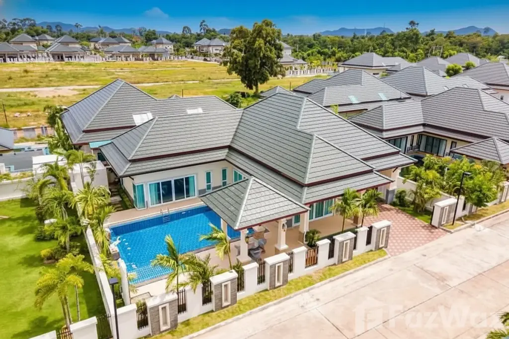 Baan Dusit Pattaya Hill 5: Aerial view of a house with a blue swimming pool, green lawn, and other houses in the background.