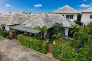 Baan Dusit Pattaya Park single-story house with a covered carport, small front yard, and a green hedge fence.