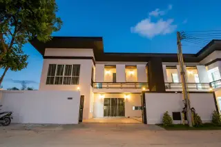 Baan Piam Mongkhon 3 modern exterior of a two-story house at dusk with illuminated balconies.