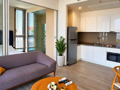 1 Bedroom Condo for Sale at Baan Plai Haad open-plan kitchen with white cabinetry, fridge, and living area with sofa