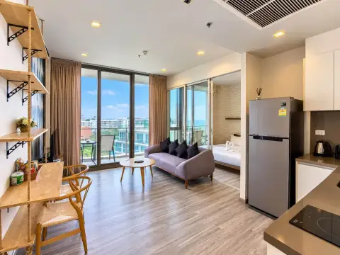 1 Bedroom Condo for Sale at Baan Plai Haad living area with sofa, dining nook, kitchen, and bedroom view with city skyline