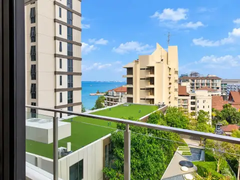 1 Bedroom Condo for Sale at Baan Plai Haad balcony view of rooftop garden, coastline, and surrounding high-rise buildings