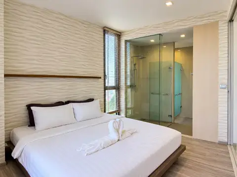 1 Bedroom Condo for Sale at Baan Plai Haad bedroom with king bed, towel swan decor, and glass-enclosed shower