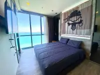 2 Bedroom Condo for Rent at Baan Plai Haad bedroom with wall-mounted TV, large bed and floor-to-ceiling sea view windows