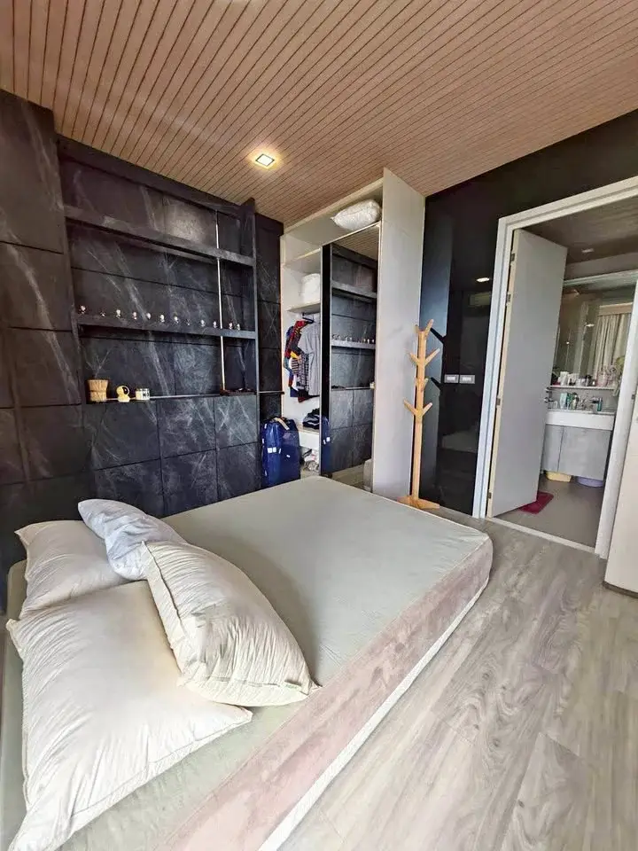 1 Bedroom Condo for Sale at Baan Plai Haad bedroom with stone accent wall, open closet and ensuite bathroom view