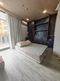 1 Bedroom Condo for Sale at Baan Plai Haad bedroom with large window, curtains and dark stone headboard wall