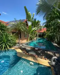 4 Bedroom House for Sale in Bang Lamung tropical garden with tiled pools, palm trees, and solar panel roof