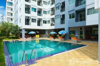 Beach 7 Condominium outdoor swimming pool with blue tiles, lounge chairs, umbrellas, and the building exterior.