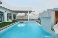 5 Bedroom House for Sale in Huai Yai pool close-up with waterfall feature, bean bag seating and white villa facade