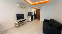 1 Bedroom Condo for Rent at C View Residence Pattaya living room with flat-screen TV, kitchenette and black leather sofa
