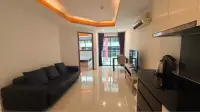 1 Bedroom Condo for Rent at C View Residence Pattaya open-plan living room with black sofa, TV and kitchenette