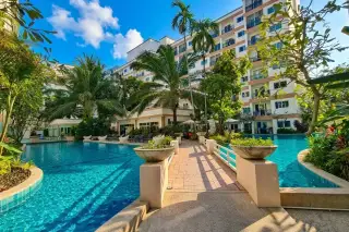 Park Lane Jomtien: Large resort-style swimming pool surrounded by palm trees, tropical foliage, and modern condo buildings.