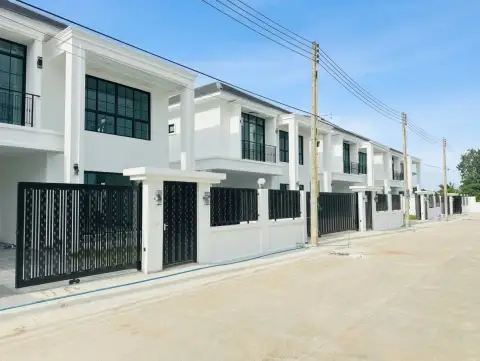 TW. Garden Hill row of modern white houses with black balconies and utility poles under a cloudy sky.