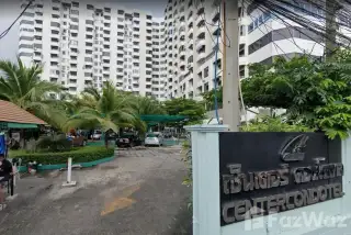 Center Condotel entrance sign, driveway with cars, palm trees, and the large residential building in the background.