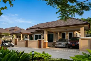 PMC Home 4 front exterior with a covered carport holding two cars, a golf cart, and lush green landscaping.