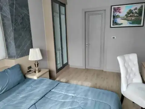 5 Bedroom House for Rent at Casa Jomtien bedroom with blue bedding, nightstand lamp, and marble accent wall