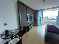Studio Condo for Sale at Centara Avenue Residence and Suites living area with TV, dining table and balcony view