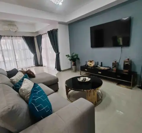 3 Bedroom House for Rent at Central Park 4 living room with gray sectional sofa, teal pillows, and wall-mounted TV