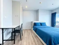 1 Bedroom Condo for Sale at Centric Sea bedroom with blue bedding, desk, chair, and city view window