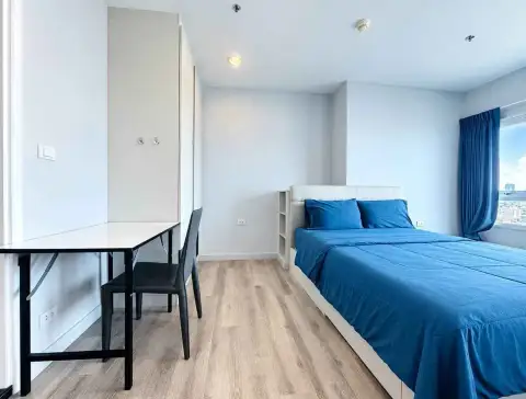 1 Bedroom Condo for Sale at Centric Sea bedroom with blue bedding, desk, chair, and city view window