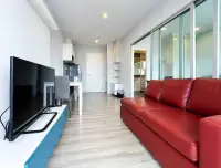 1 Bedroom Condo for Sale at Centric Sea living room with red leather sofa and glass sliding doors