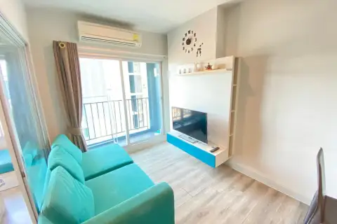1 Bedroom Condo for Rent at Centric Sea lounge area with turquoise sofa, TV unit, and balcony access