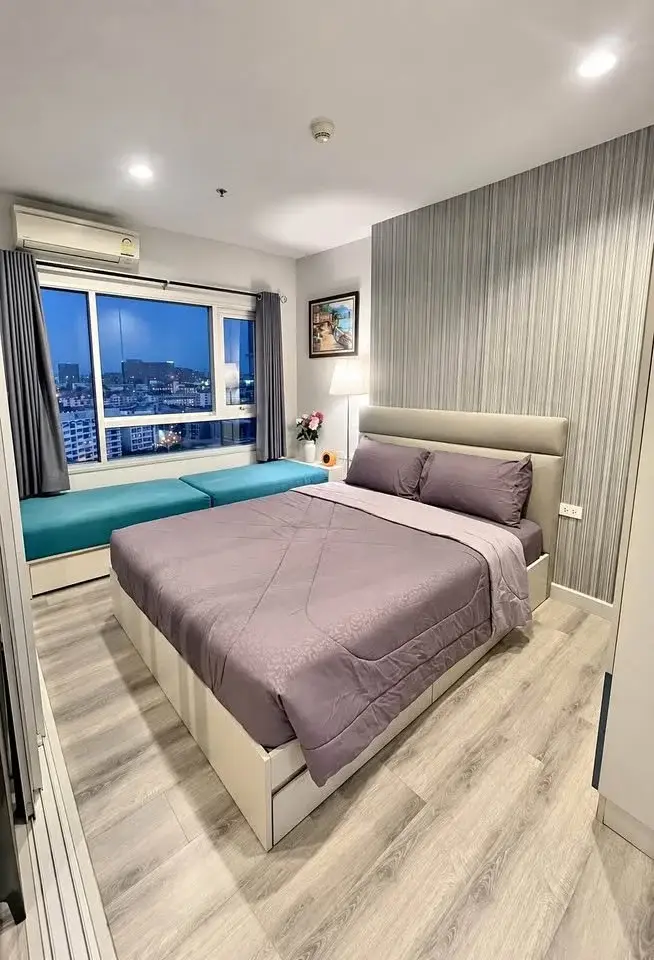 1 Bedroom Condo for Sale at Centric Sea bedroom with purple bedding, city night view, and window seat