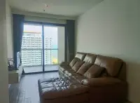 1 Bedroom Condo for Sale at Cetus Beachfront living room with brown sofa and large window overlooking sea and towers
