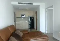 1 Bedroom Condo for Sale at Cetus Beachfront living area with leather sofa and open kitchen with fridge